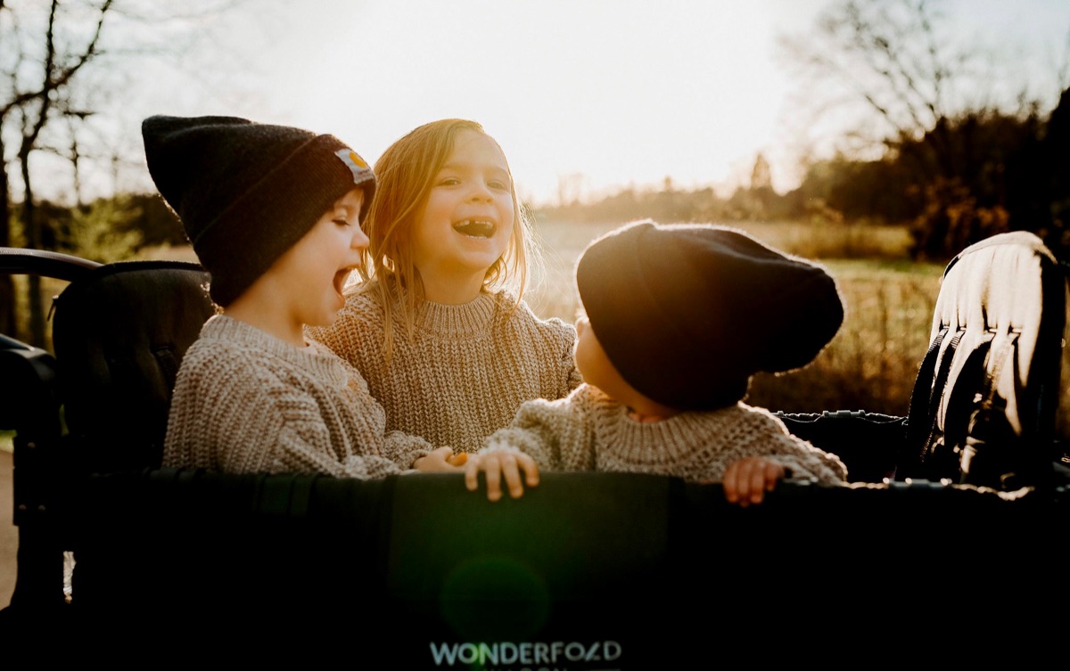 Children smiling while riding in a WonderFold stroller wagon.